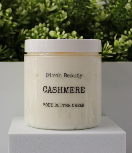 Jar of 'Cashmere' body butter cream with 'Birch Beauty' branding on a light surface with greenery in the background. Handmade in Rhode Island. Made with limited ingredients.