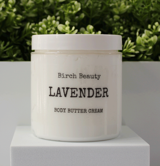 Jar of 'Lavender' body butter cream with 'Birch Beauty' branding on a light surface with greenery in the background. Handmade in Rhode Island.