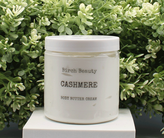 Jar of 'Cashmere' body butter cream with 'Birch Beauty' branding on a light surface with greenery in the background. Handmade in Rhode Island. Made with limited ingredients.