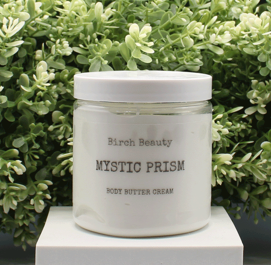 Jar of 'Mystic Prism' body butter cream with 'Birch Beauty' branding on a light surface with greenery in the background. Handmade in Rhode Island. Made with limited ingredients.