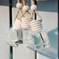 Decorative hanging with glass bottles and wooden beads against a neutral background